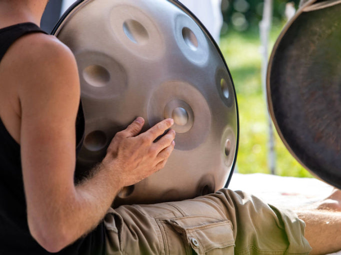 Handpan Musiker spielt in der Sonne erholsame Klänge auf einer Edelstahl Handpan in 432 Hz zum Auftanken und Entspannen