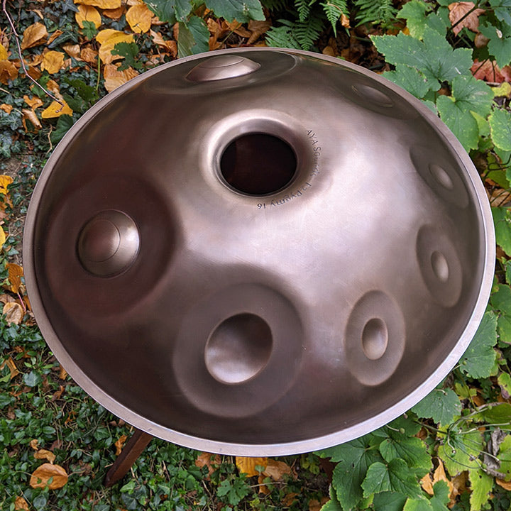 AYA Sounds Handpan aus Embersteel steht mit der Rückseite nach oben zwischen Pflanzen auf einem Handpan Ständer