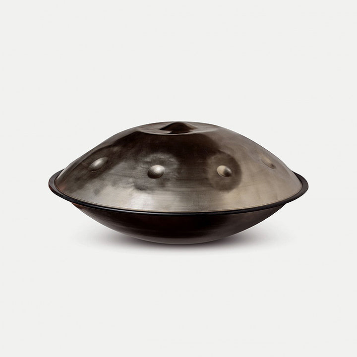 Healing Frequency Handpan aus einem silbernen Edelstahl mit 9 Tonfeldern von der Seite auf einem weißen Hintergrund.