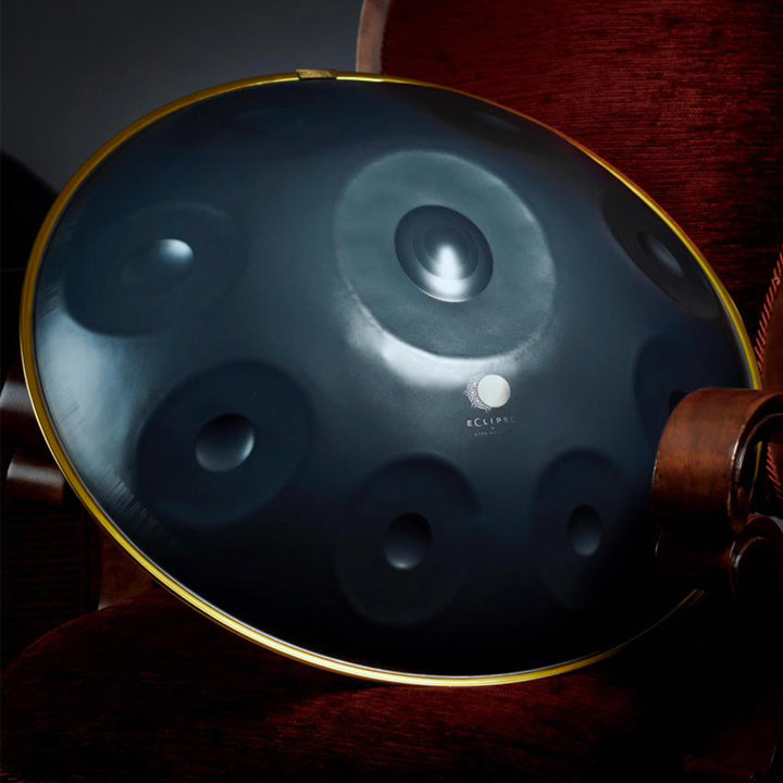 Nitrierte Eclipse Handpan Drum liegt schön belichtet auf einem Königssessel. Diese Pantam ist ein Perfektes Anfänger Instrument. Sichere dir diese günstige Handpan jetzt bei uns im Shop.