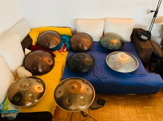 Acht Handpans liegen auf einer Couch im Handpan Showroom Innsbruck zum Probespielen bereit