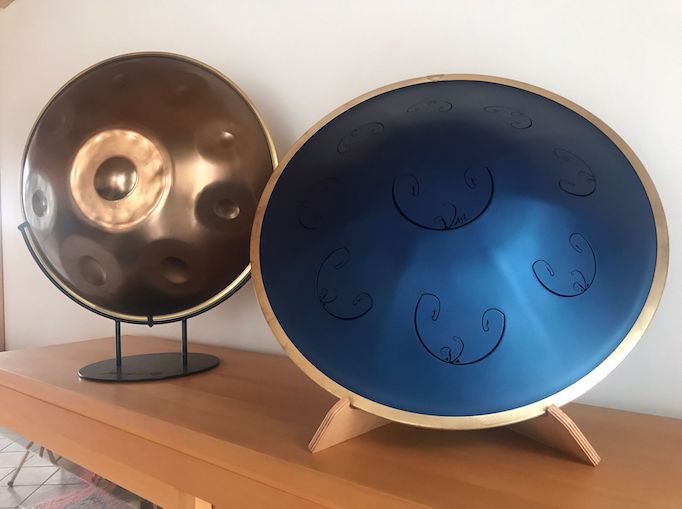 Eine blau metallisch glänzende Tongue Drum und eine Handpan aus Edelstahl ausgestellt im Handpan Showroom Bonn