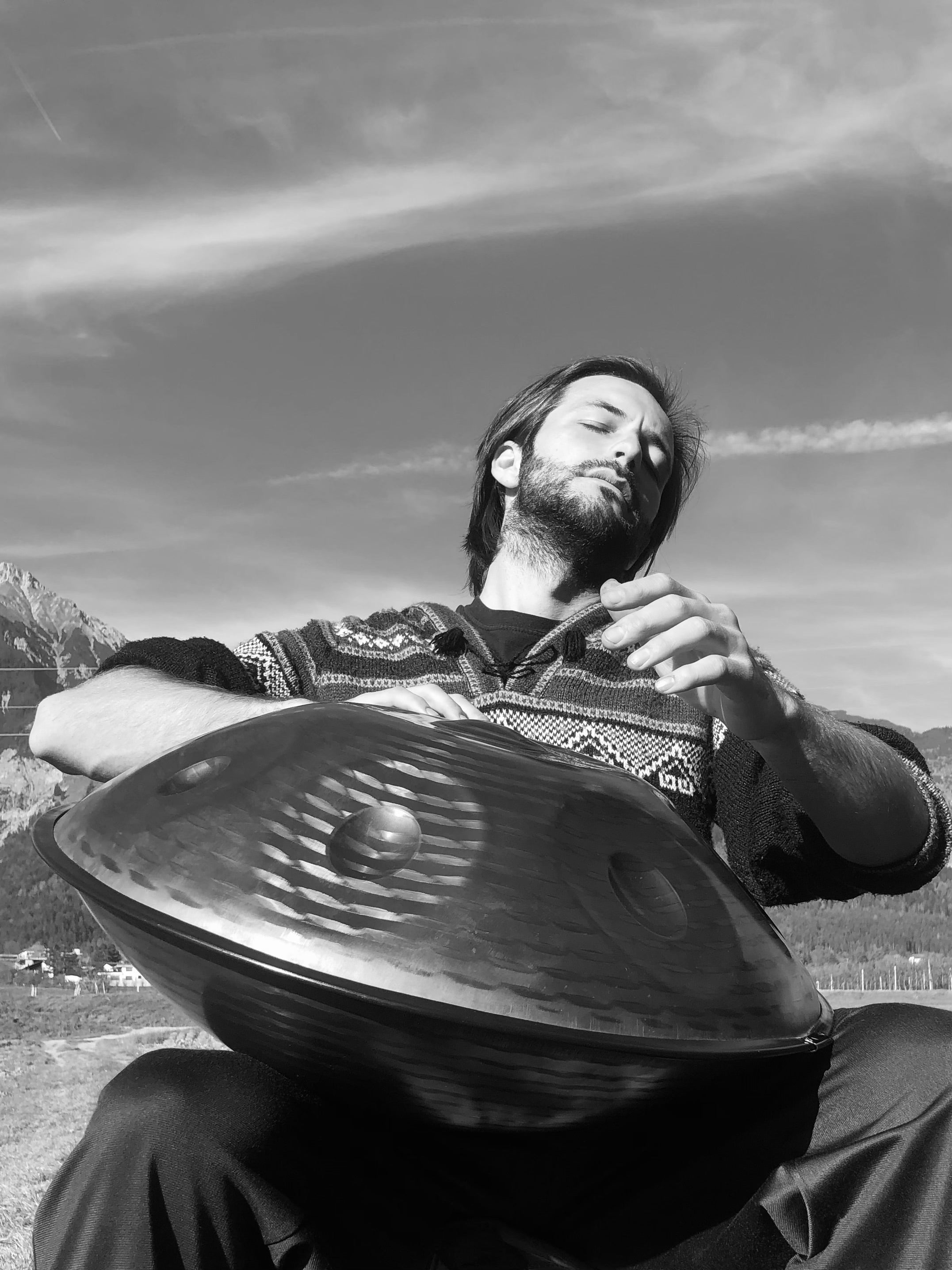 Leidenschaftlich spielt ein Handpan.World Vertreter in den Bergen in der Natur auf einer Handpan.