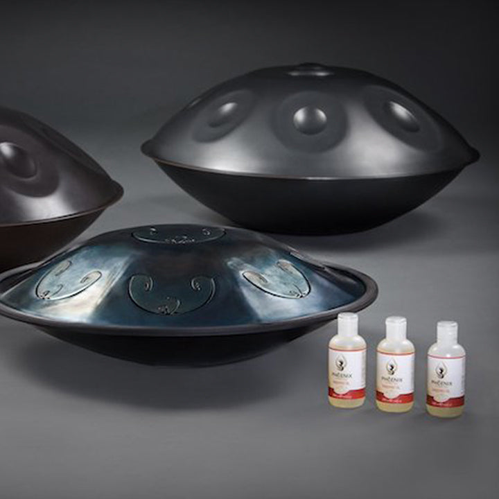 Zwei Handpan Drum Instrumente und eine Rav Vast Zugentrollen stehen neben drei Flaschen voll mit 250ml Phoenix Handpan Pflege Öl, bereit gereinigt und gegen Rost geschützt zu werden.