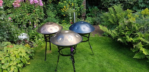 Drei Handpans auf Ständern stehen in einem Garten zum Probespielen und azsprobieren bereit