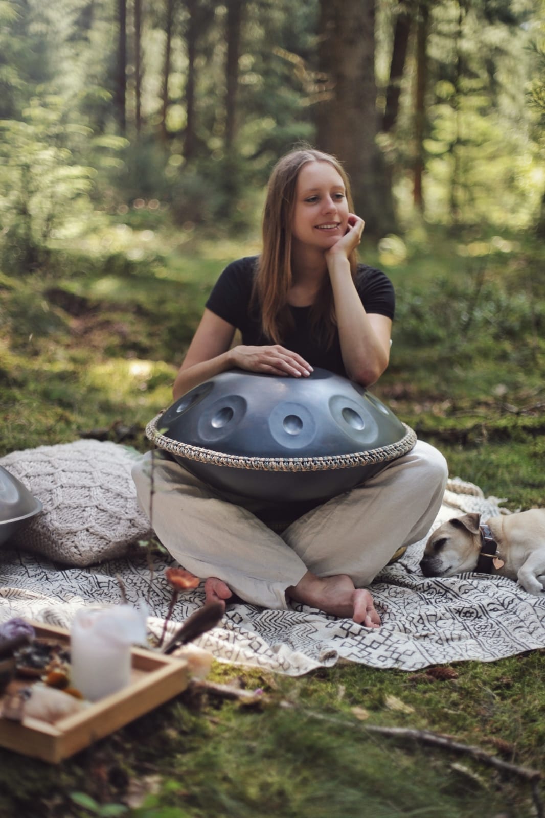 Die Handpan Vertreterin aus Bochum sitzt im grünen auf einem Tuch und hat eine Handpan auf ihrem Schoß. Handpan ausprobieren und kaufen in Bochum.