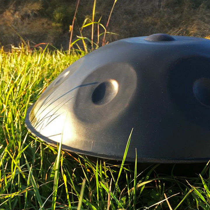 Eine nitrierte Handpan liegt auf dem Gras in der Sonne in einer natürlichen Umgebung.