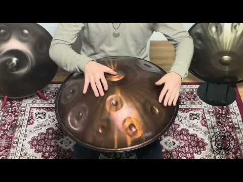 Ein Handpan-Spieler sitzt auf einem kunstvoll gestalteten Teppich, umgeben von Handpans, während er den schönen Klang des Aelo D Celtic Minor Mutant Handpans demonstriert.