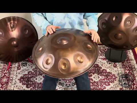 Ein Mann spielt eine wunderschöne NamiPan Handpan, während er zwischen zwei glänzenden Handpans auf einem kunstvoll gemusterten Teppich sitzt.