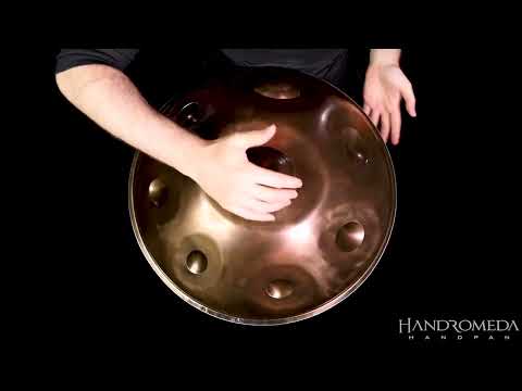 Erlebe die bezaubernden Klänge der Handromeda A2 Aegean Handpan, gespielt von einem talentierten Musiker. Die Handromeda, ein Meisterwerk aus Sao Paulo, vereint Kreativität und Innovation und bringt die seelenvollen Schwingungen des Metalls perfekt zur Geltung. Gegründet von Vitor Luz, seit 2017.