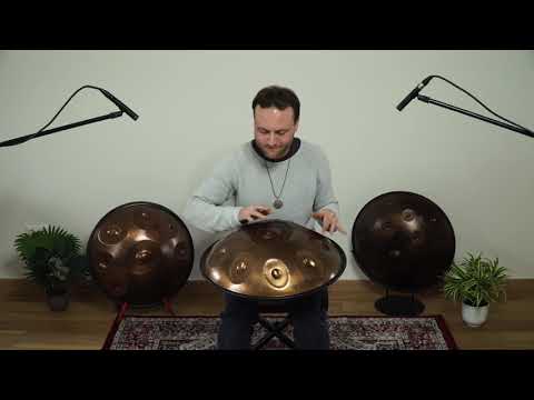 Zu sehen ist ein Mann, der eine gold schimmernde Spirit Soul C# Kurd 9 spielt. Im Hintergrund stehen Pflanzen und zwei weitere Handpans vor einer weißen Wand. 