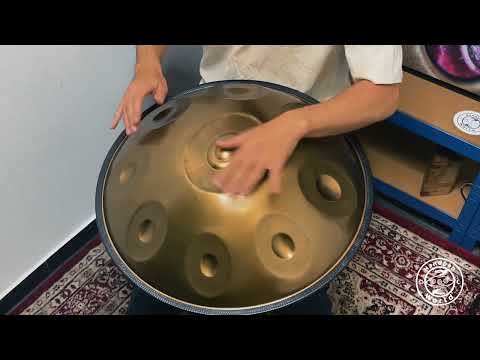 Ein Mann spielt gekonnt ein Spirit Soul C# Kurd 9 Noten 432Hz 'Healing Frequency' Handpan. Die Handpan schimmert im Licht, während der Handpanspieler eine schöne Melodie improvisiert.