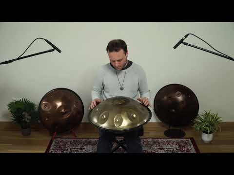 Mann sitzt in schön dekoriertem Zimmer von einer Silber golden schimmernden Edelstahl Handpan namens Spirit Sould B2 Celtic Minor / Amara 9 Edelstahl 440Hz. Im Hintergrund sind zwei weitere Handpans und Pflanzen zu sehen.