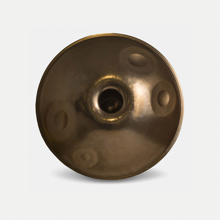 Healing-Frequency-Handpan B2 Minor mit 13 Tonfeldern gold schimmernd, vor weißem Hintergrund, aus der Bodenansicht. Sichtbar ist die Unterschale der Handpan mit 4 Bottomnotes 