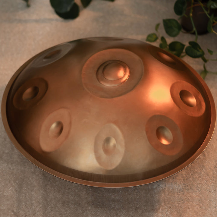 Eine bronzefarbene Nala Handpan liegt in einem gemütlichen Raum auf einem beigen Teppich