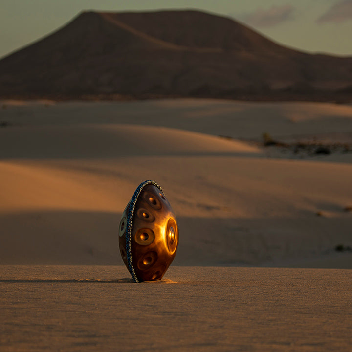 Weitaufnahme von Namipan Handpan im Sand der Wüste bei Sonnenuntergang.