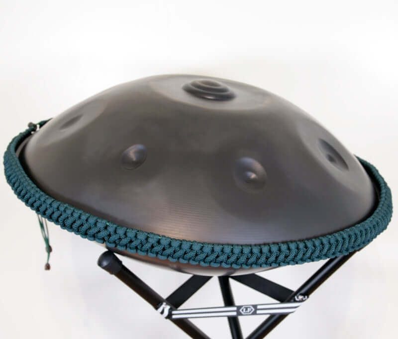 nitrierte, schwarze Handpan mit Handpan Rope auf einem Holzständer. Das Rope ist in der Farbe Smaragd.