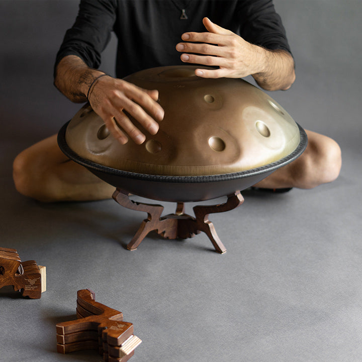 Eine Handpan auf einerm hölzernen Handpan Floorstand von Katanui steht auf dem grauen Boden.