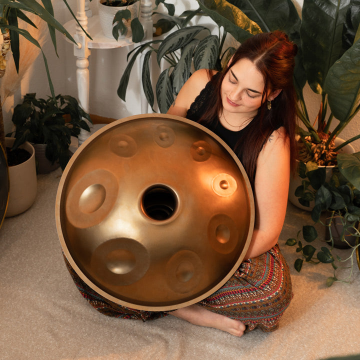 Eine Handpanspielerin zeigt die mit Bottomnotes bestückte Unterseite einer Handgefertigten Nala Handpan. Tauche ein in die faszinierende Welt der Handpans mit Handpan.World.