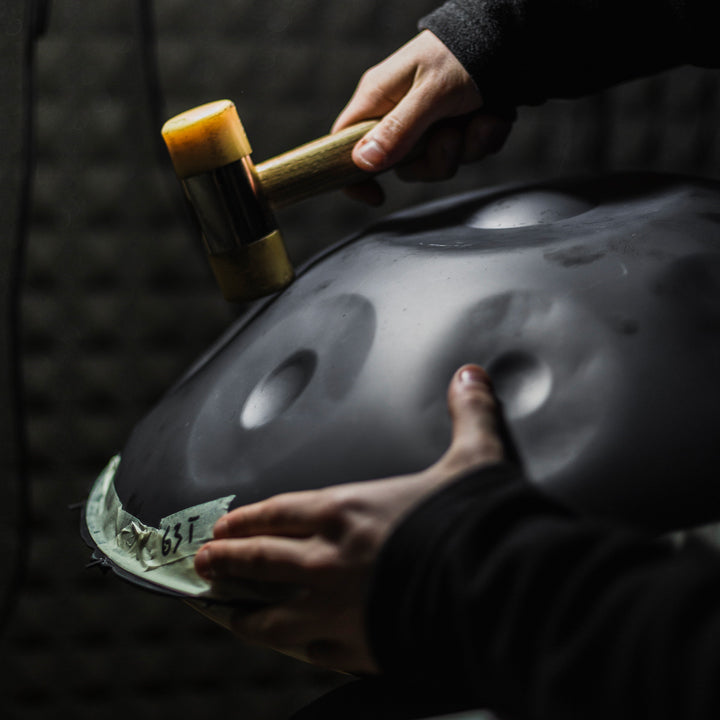 Handmaker Maker arbeitet an einer nitrierten Black Magic Handpan mit einem Hammer