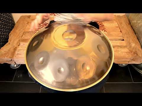 Handpanspieler spielt auf einer Edelstahl Handpan mit der Stimmung C Celtic Minor. Er sitzt auf einem hölzernen Wagen. Diese Handpan, sowie viele weitere kann man online im Handpan.World Store kaufen.