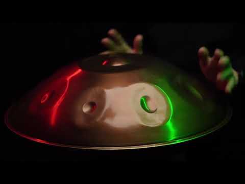 Handpanspieler spielt auf einer Spirit Wave D Kurd, die von roten und grünen Lichtern angestrahlt wird. Diese Handpan, sowie viele weitere kann man online im Handpan.World Store kaufen.