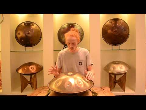 Rothaariger Handpanspieler spielt auf einer Magical D Celtic Minor mit 9 Tonfeldern. Um ihn herum befinden sich sieben weitere Handpans.