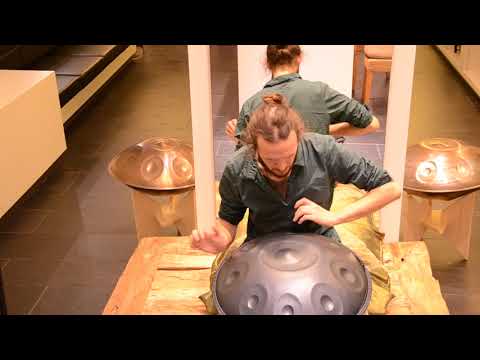 Handpanspieler spielt auf einer nitrierten NamiPan C# Kurd. Er sitzt im Handpan Showroom München und neben ihm stehen zwei weitere Handpans.